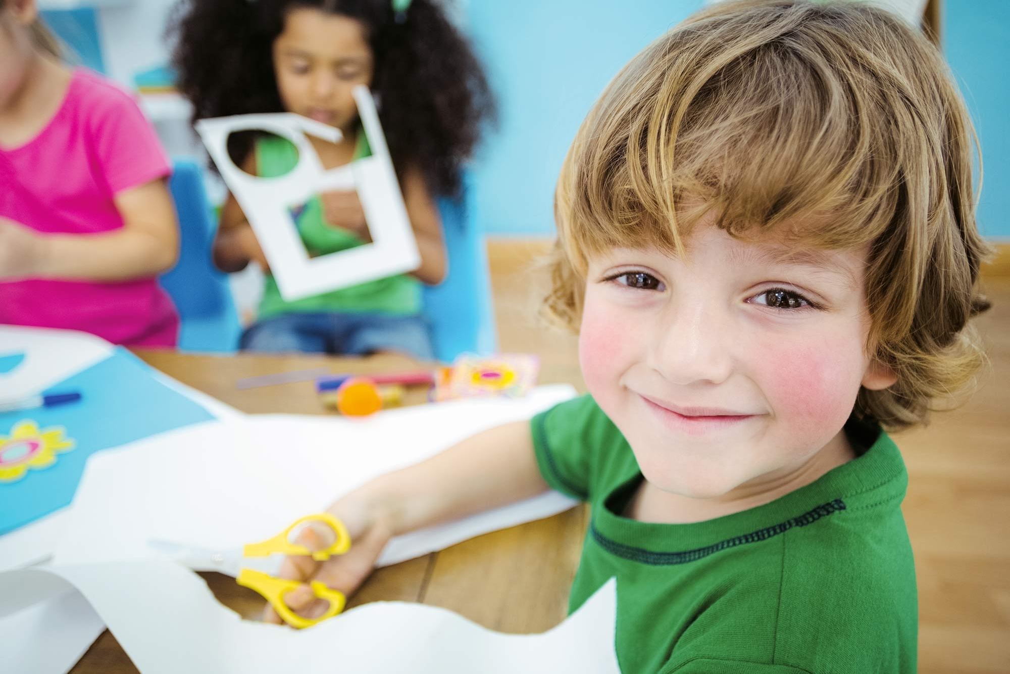 Drei Kleinkinder schneiden Papier mit einer Schere