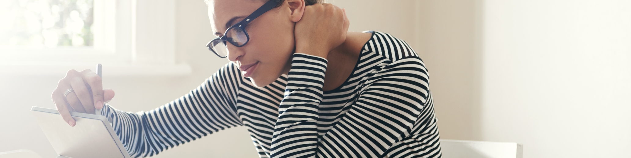 Frau sitzt an einem Tisch vor einem Tablet