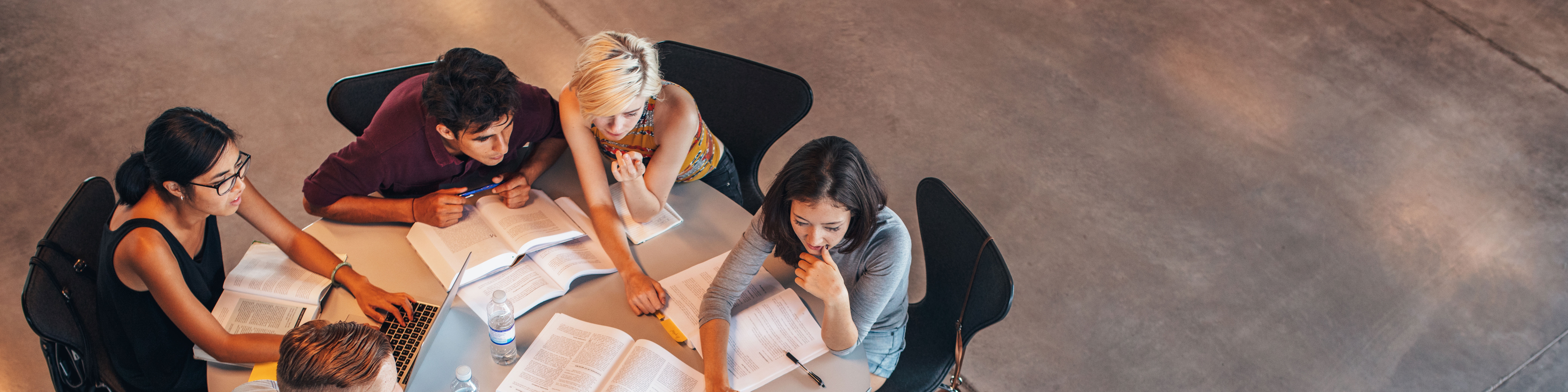 Fünf Studierende sitzen an einem runden Tisch und lernen gemeinsam