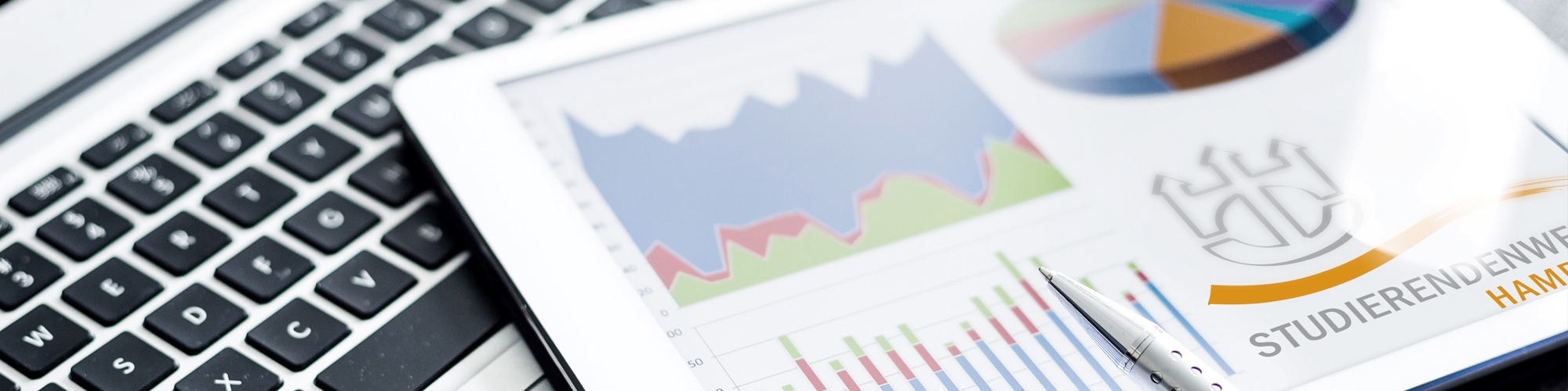 Aufgeklappter Laptop mit Zeitung und Stift 