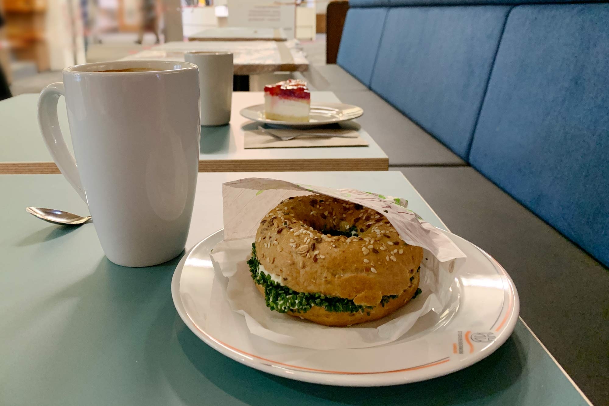 Bagel auf einem Teller mit Kaffeetasse daneben