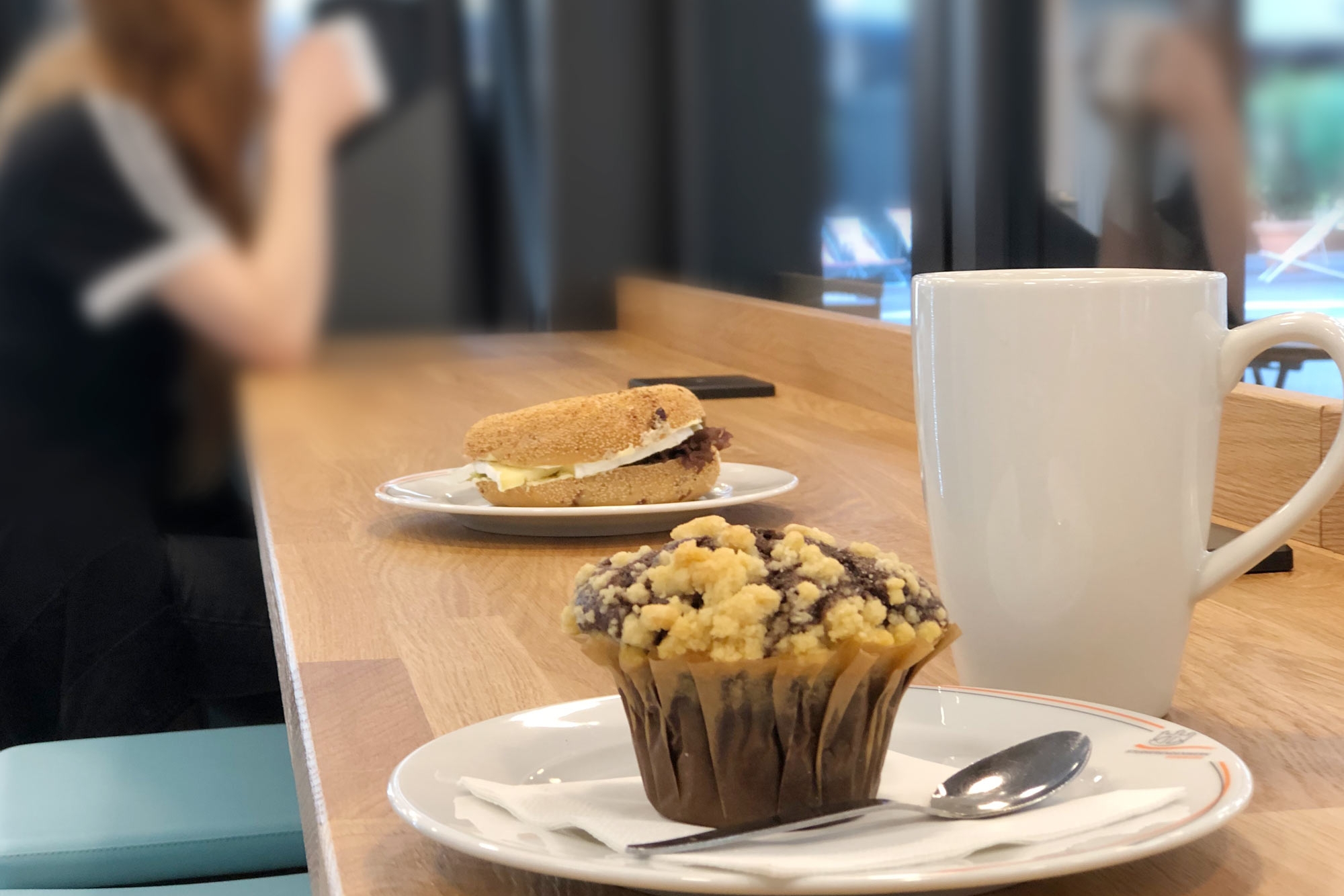 Muffin, Bagel und eine Tasse Kaffee auf einem Tisch im CampusCafé