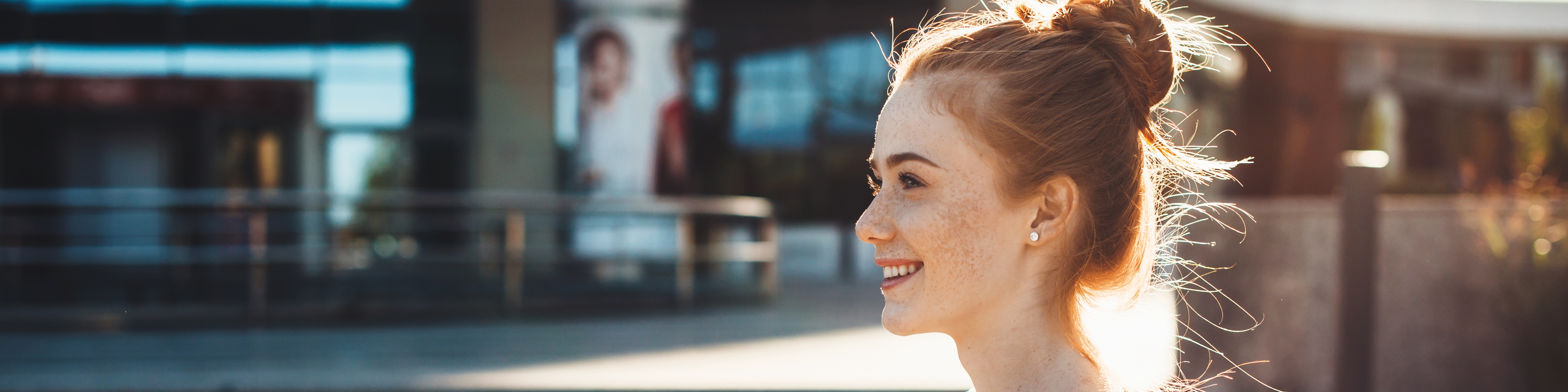 Junge Frau steht vor einem Gebäude und hält Bücher in den Händen
